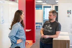 TACO team members Jeff and Julie discussing lessons learned in the office hallway